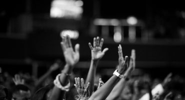 photo in black and white with people in a crowd raising their hands