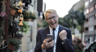 man looking at his phone looking excited